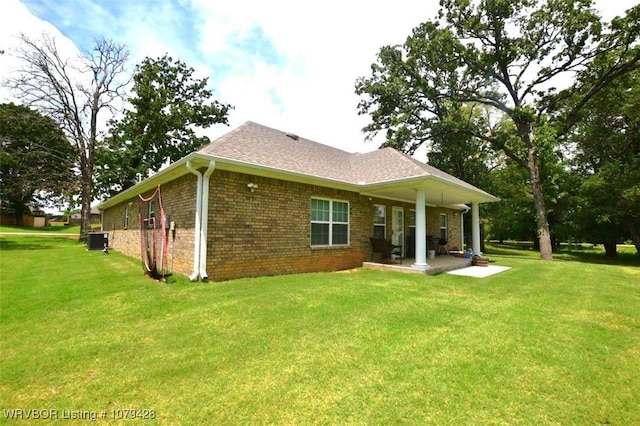 1111 Ridge Dr, Stilwell, OK 74960 - back of house featuring brick siding, a lawn, central air condition unit, and a shingled roof