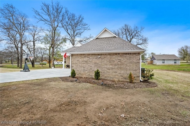 1111 Ridge Dr, Stilwell, OK 74960 - view of property exterior with a shingled roof, brick siding, a yard, and concrete driveway