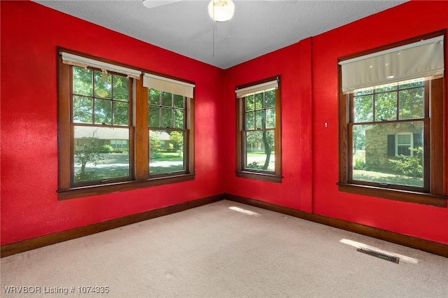 carpeted empty room with ceiling fan and a textured ceiling