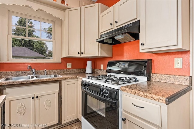 kitchen with white gas range, sink, and light tile patterned floors