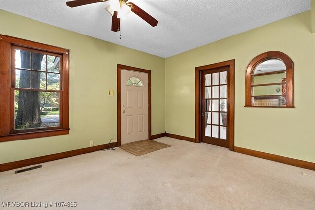 entrance foyer with light carpet, a textured ceiling, and ceiling fan