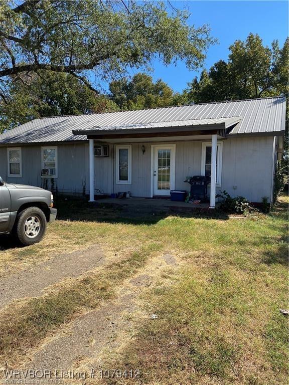 ranch-style home with metal roof, a front yard, and a wall unit AC