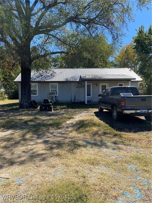 ranch-style house with metal roof and a front lawn