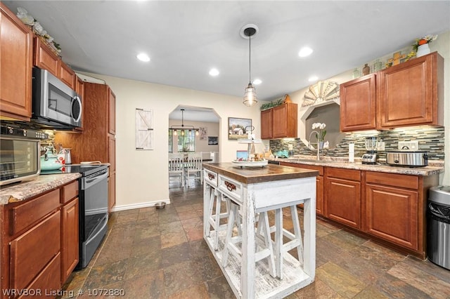 kitchen with pendant lighting, sink, appliances with stainless steel finishes, and tasteful backsplash