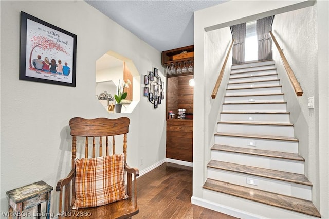 staircase featuring wood-type flooring and a textured ceiling