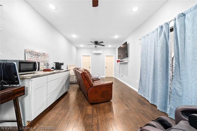 living room featuring ceiling fan, dark hardwood / wood-style flooring, and an AC wall unit