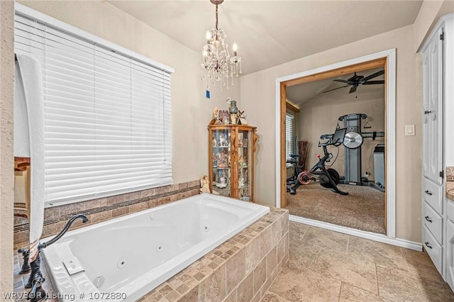 bathroom featuring a relaxing tiled tub, ceiling fan with notable chandelier, and vanity