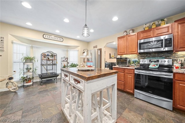 kitchen with appliances with stainless steel finishes, backsplash, and pendant lighting