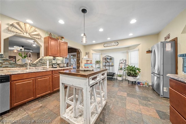 kitchen with sink, appliances with stainless steel finishes, tasteful backsplash, butcher block countertops, and decorative light fixtures