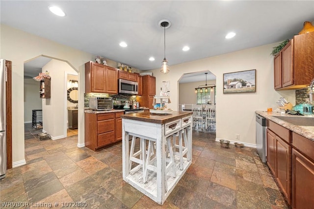 kitchen with stainless steel appliances, hanging light fixtures, and tasteful backsplash