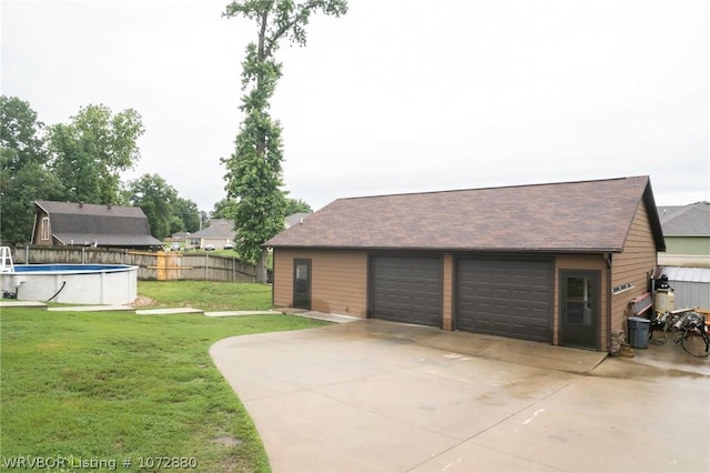 garage with a fenced in pool and a lawn