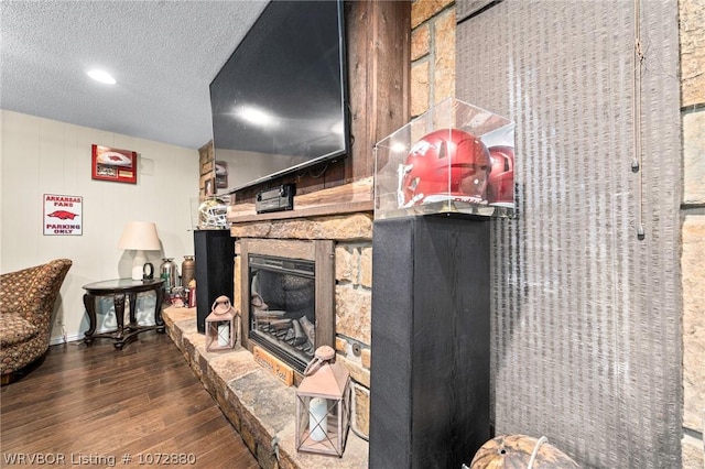 room details featuring wood-type flooring, a textured ceiling, and a stone fireplace