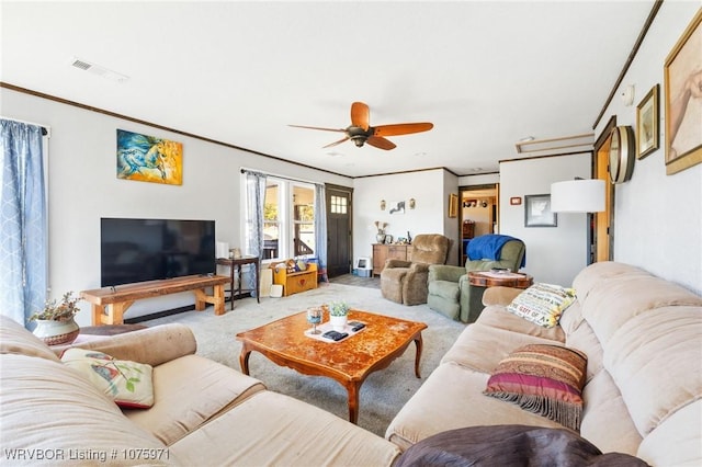 living room featuring carpet floors, ceiling fan, and ornamental molding