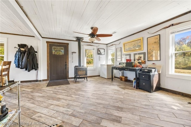 interior space with a wood stove, ceiling fan, wood ceiling, and light hardwood / wood-style floors