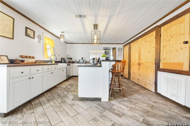 kitchen with a kitchen breakfast bar, stainless steel dishwasher, decorative light fixtures, a center island, and white cabinetry