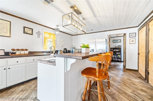 kitchen with white cabinetry, wooden ceiling, a kitchen island, hanging light fixtures, and stainless steel refrigerator