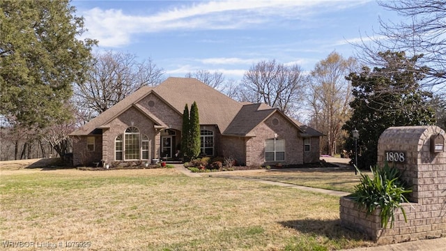 view of front facade with a front lawn, brick siding, and a shingled roof