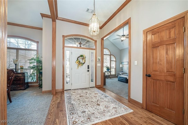 foyer entrance featuring light wood finished floors, visible vents, ornamental molding, baseboards, and ceiling fan with notable chandelier
