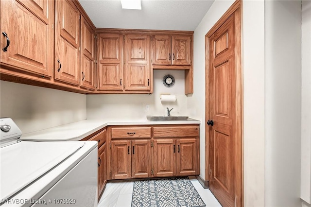 laundry room with light tile patterned floors, a sink, washer / clothes dryer, and cabinet space