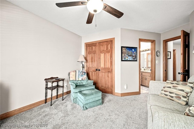 carpeted living area featuring a ceiling fan and baseboards