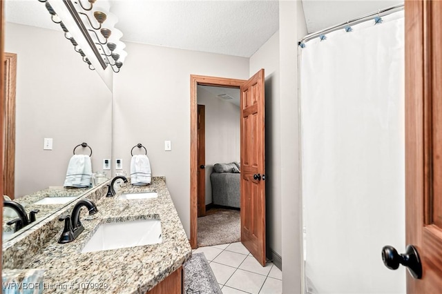 bathroom featuring double vanity, a textured ceiling, tile patterned floors, and a sink