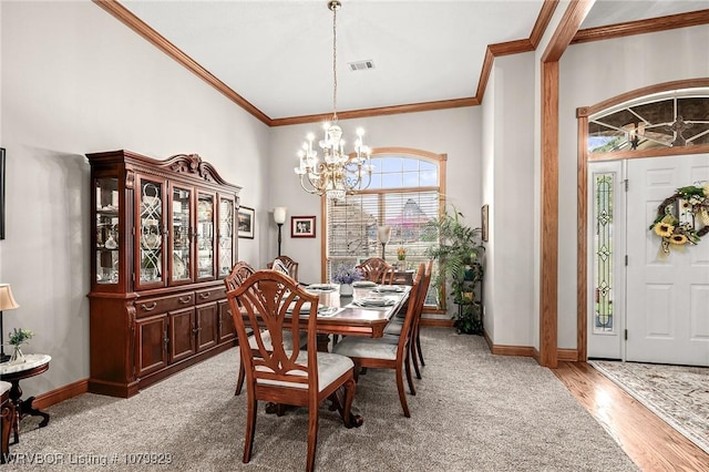 dining area featuring visible vents, light carpet, crown molding, baseboards, and a notable chandelier