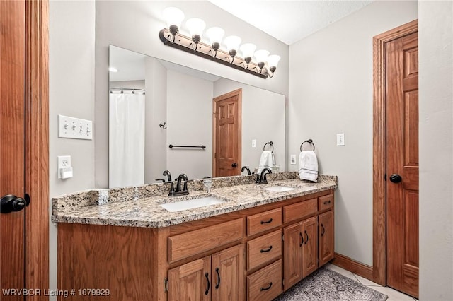 full bath featuring baseboards, tile patterned flooring, a sink, and double vanity