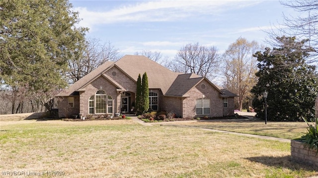 ranch-style home featuring brick siding, a shingled roof, and a front yard
