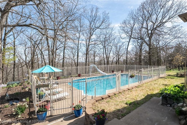 view of pool featuring fence, a fenced in pool, a water slide, and a patio