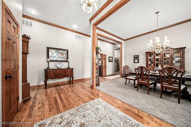 dining room with a chandelier, wood finished floors, visible vents, and crown molding