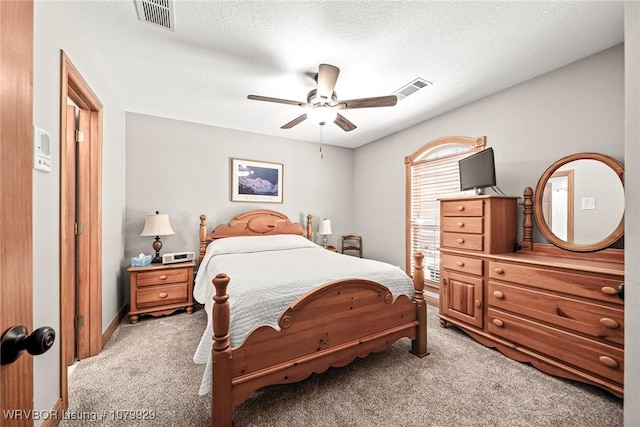bedroom with a textured ceiling, visible vents, and light carpet