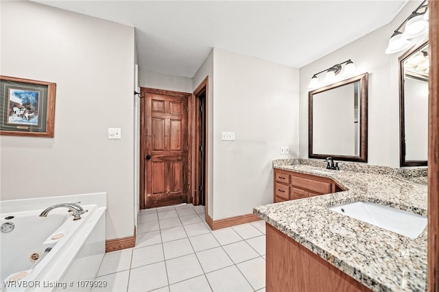 full bath featuring baseboards, tile patterned flooring, a sink, and a jetted tub
