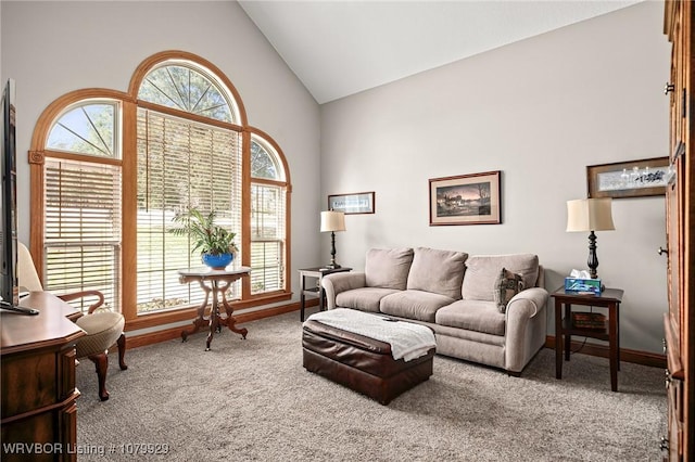 carpeted living room featuring baseboards and high vaulted ceiling