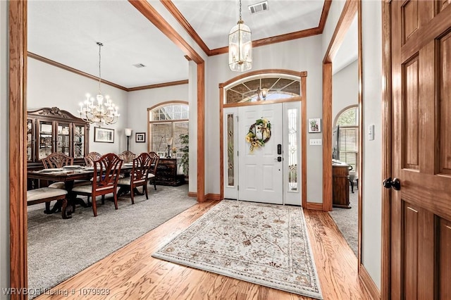 foyer featuring a chandelier, light wood-type flooring, visible vents, and ornamental molding