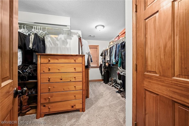 walk in closet with visible vents and light colored carpet