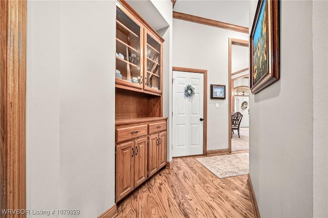 hall with baseboards, crown molding, and light wood finished floors