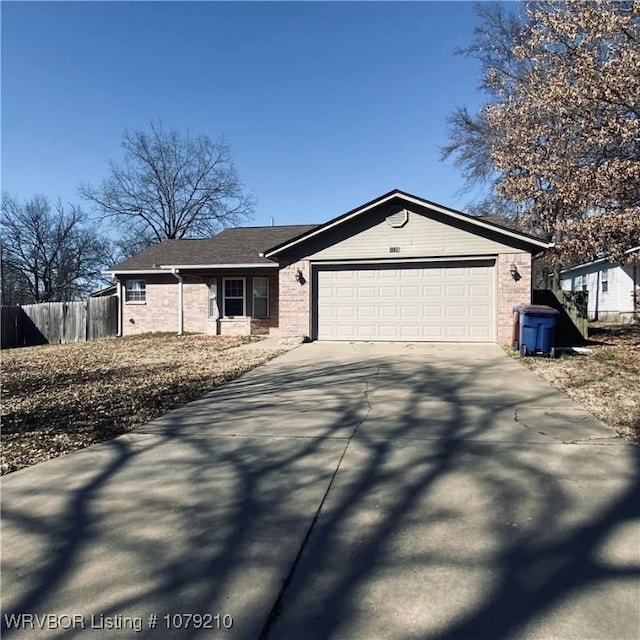 ranch-style house featuring a garage, brick siding, driveway, and fence