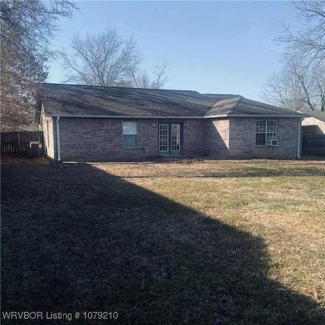 ranch-style home with a front yard, brick siding, fence, and central AC unit