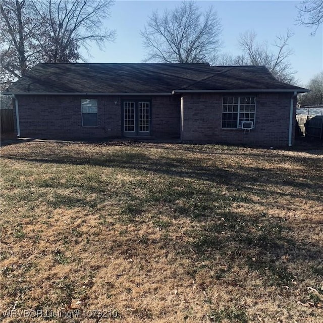 back of property with a yard, brick siding, and fence