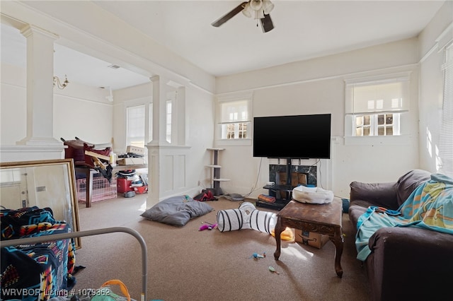 living area with carpet, decorative columns, a healthy amount of sunlight, and ceiling fan