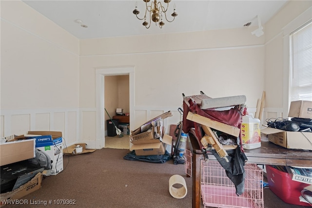 interior space featuring carpet flooring, a decorative wall, an inviting chandelier, and a wainscoted wall