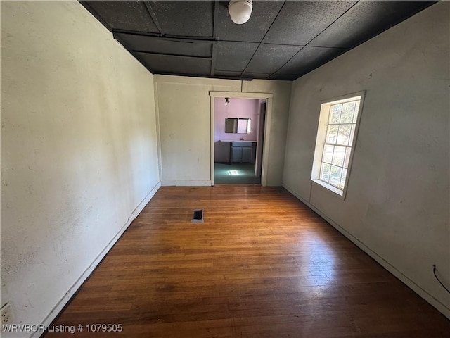 empty room featuring wood finished floors, visible vents, and a drop ceiling