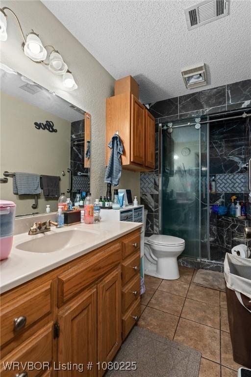 bathroom featuring a stall shower, visible vents, a textured ceiling, and toilet