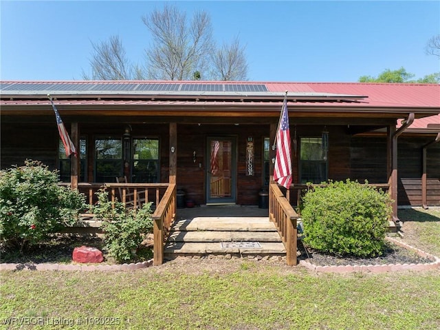 view of front of house with roof mounted solar panels, covered porch, and metal roof