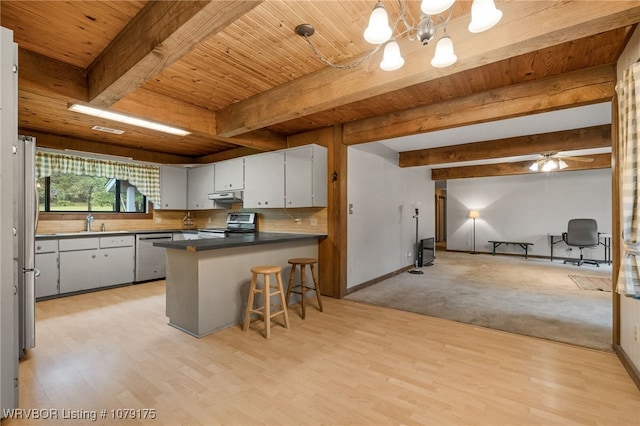 kitchen featuring under cabinet range hood, a peninsula, stainless steel appliances, open floor plan, and dark countertops