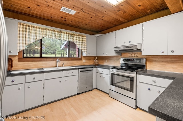 kitchen with dark countertops, visible vents, appliances with stainless steel finishes, a sink, and under cabinet range hood