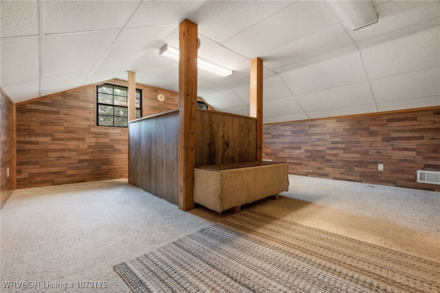 bonus room with carpet floors, lofted ceiling, visible vents, and wood walls