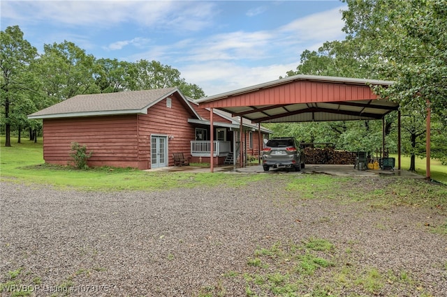 view of front of house with french doors, gravel driveway, and a detached carport