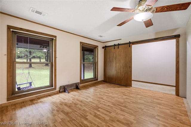 unfurnished room featuring light wood finished floors, baseboards, visible vents, and crown molding