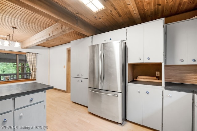 kitchen featuring dark countertops, wooden ceiling, beamed ceiling, freestanding refrigerator, and white cabinetry